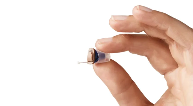 Homem segurando aparelho auditivo IIC
