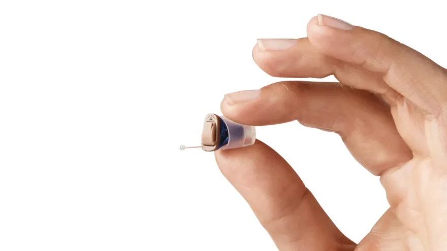 Homem segurando aparelho auditivo IIC